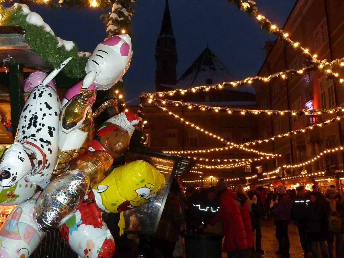 Salzburg Cathedral silhouetted against festive market lights in winter