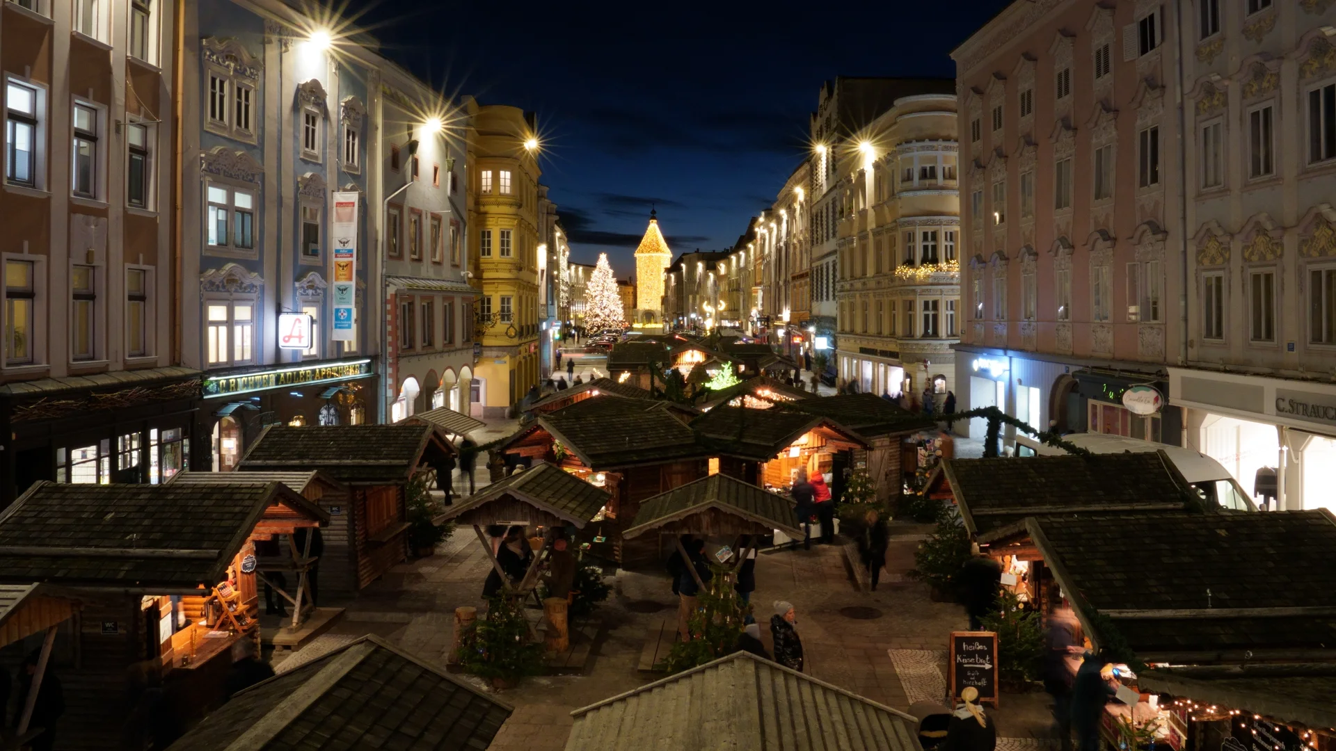 Welser Weihnachtswelt illuminated stalls in Wels at twilight with Rathaus tower and Christmas tree