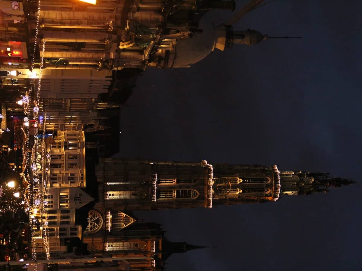 Antwerp Cathedral spire shines over the festive Christmas market at twilight