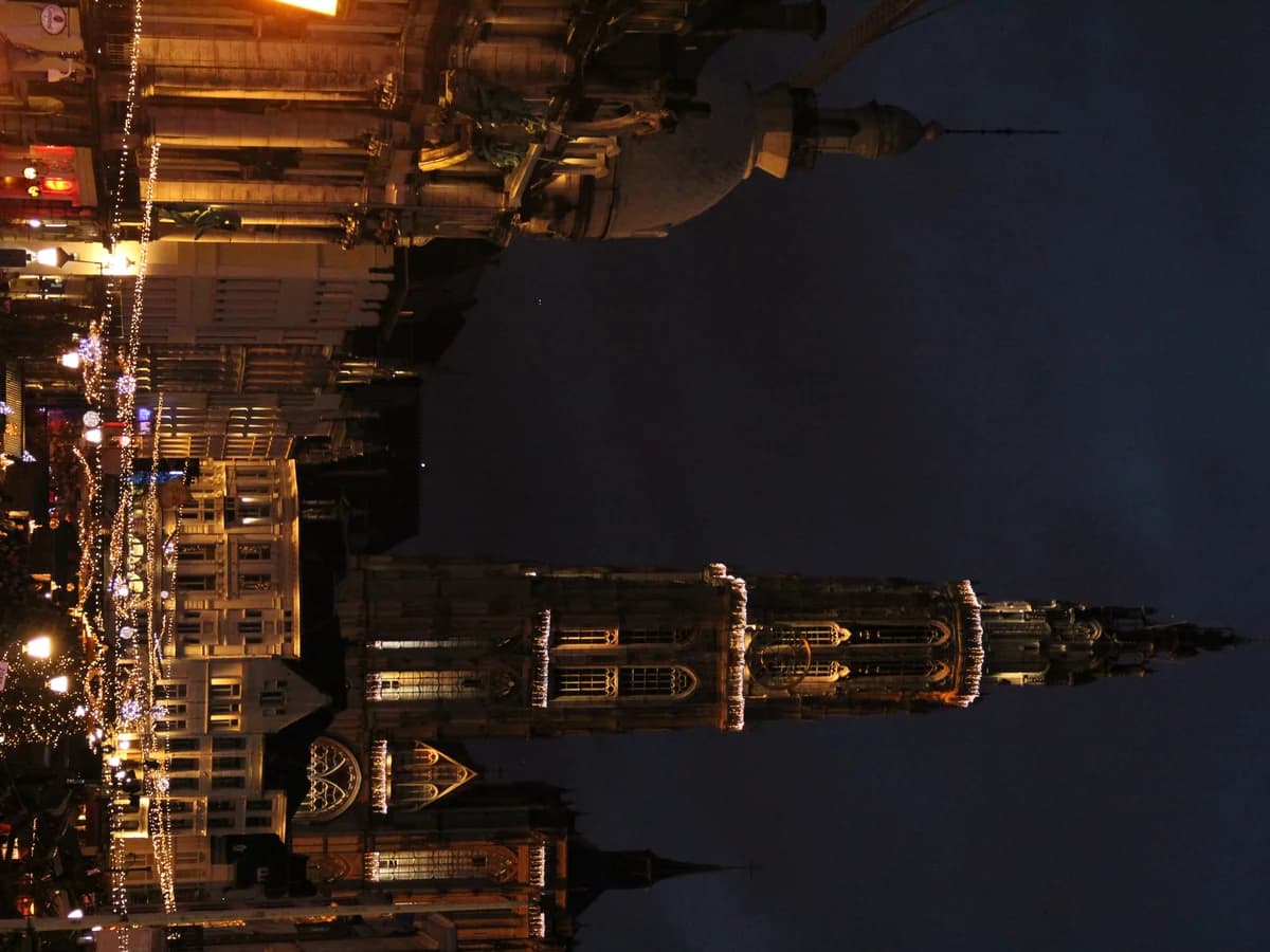 Antwerp Cathedral spire shines over the festive Christmas market at twilight