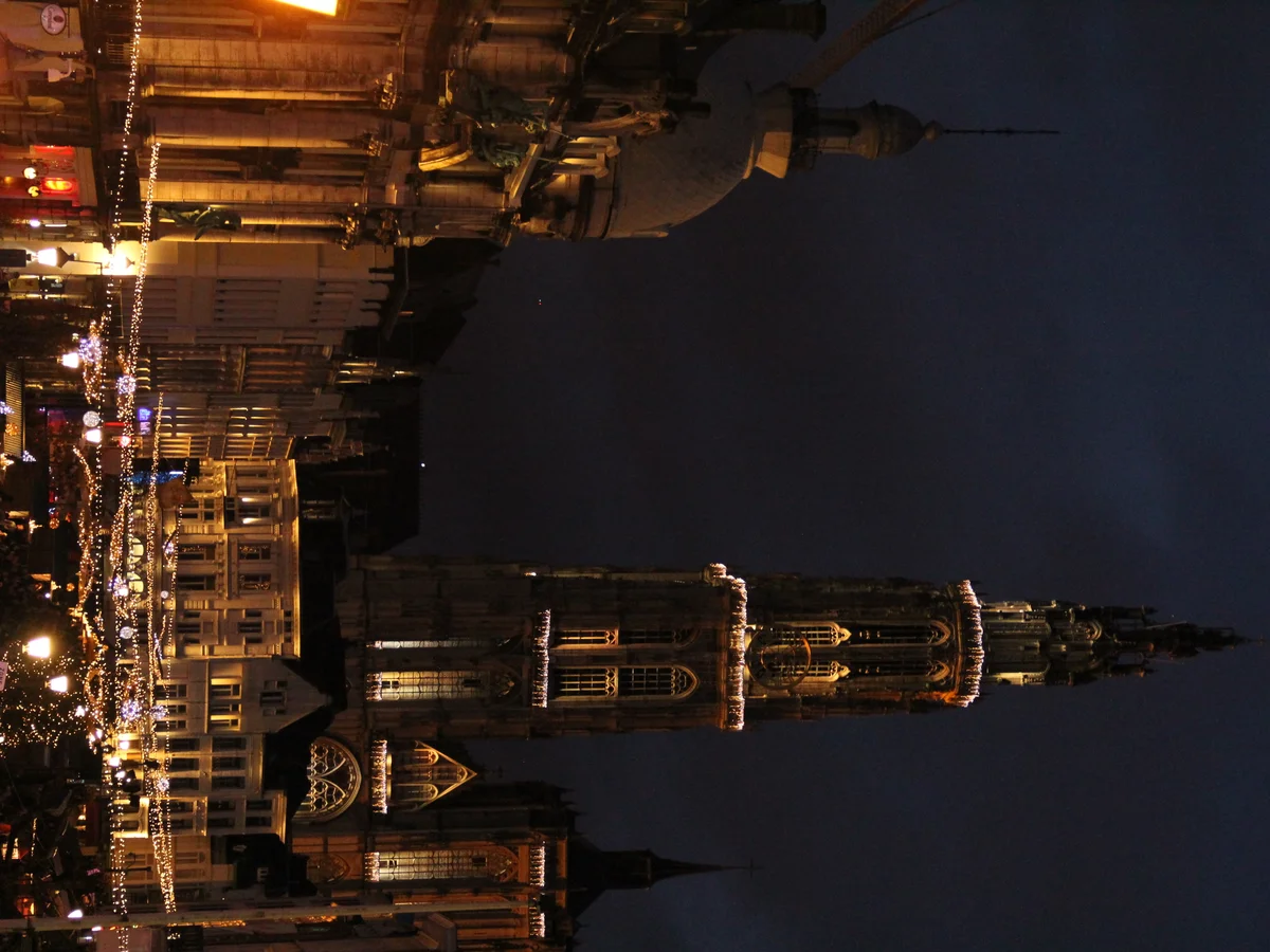 Antwerp Cathedral spire shines over the festive Christmas market at twilight