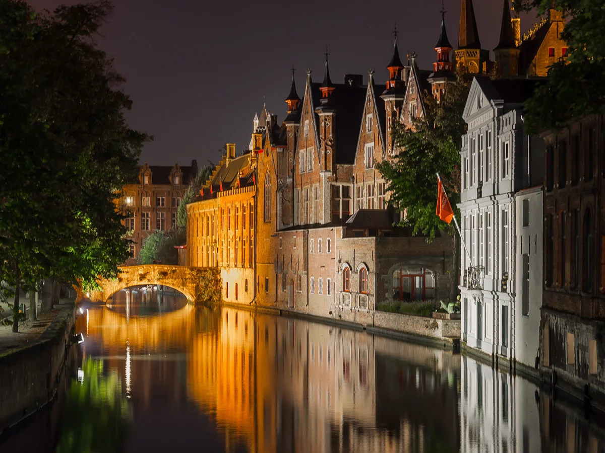 Bruges canal at blue hour with medieval architecture and warm lighting