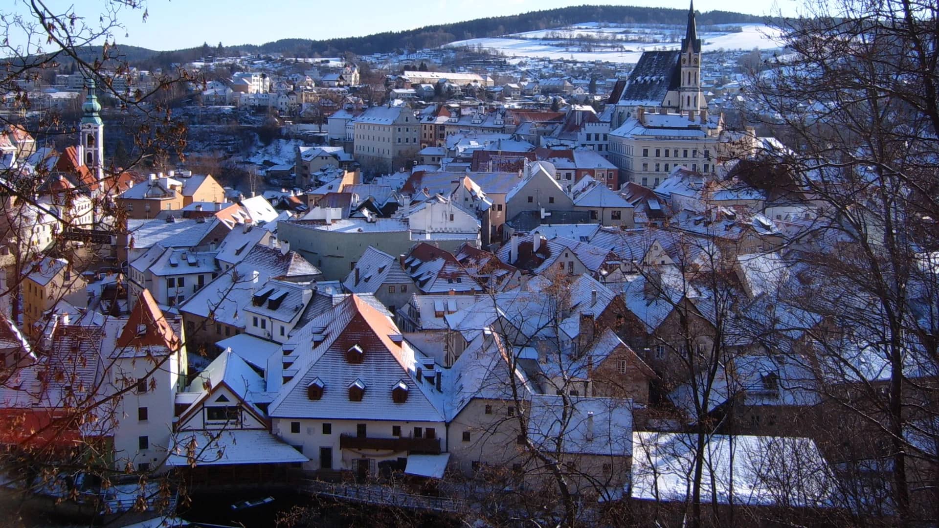 Český Krumlov skyline with church spire blanketed in winter snow