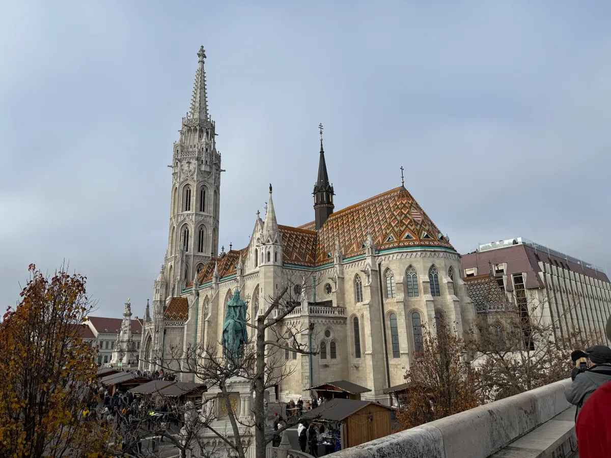 Unknown Christmas market scene with Matthias Church, festive decorations, and stalls under overcast skies.