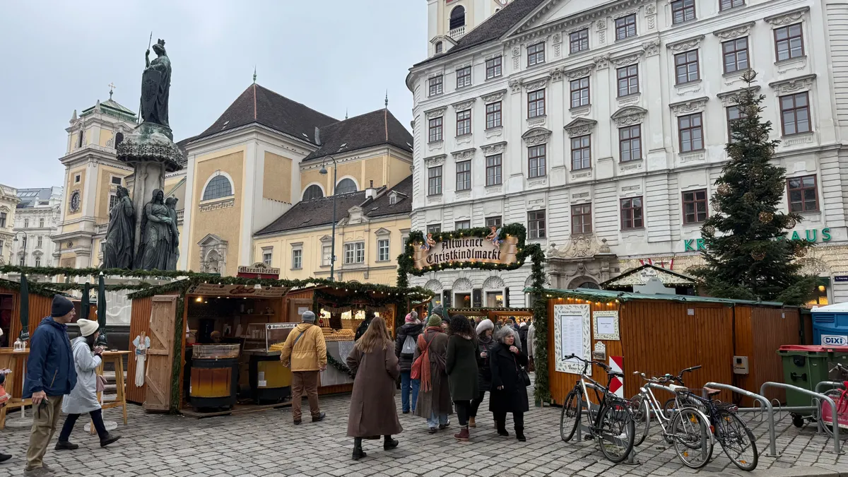 Festive decorations and lights at an unknown Christmas market with wooden stalls in a historic European square.