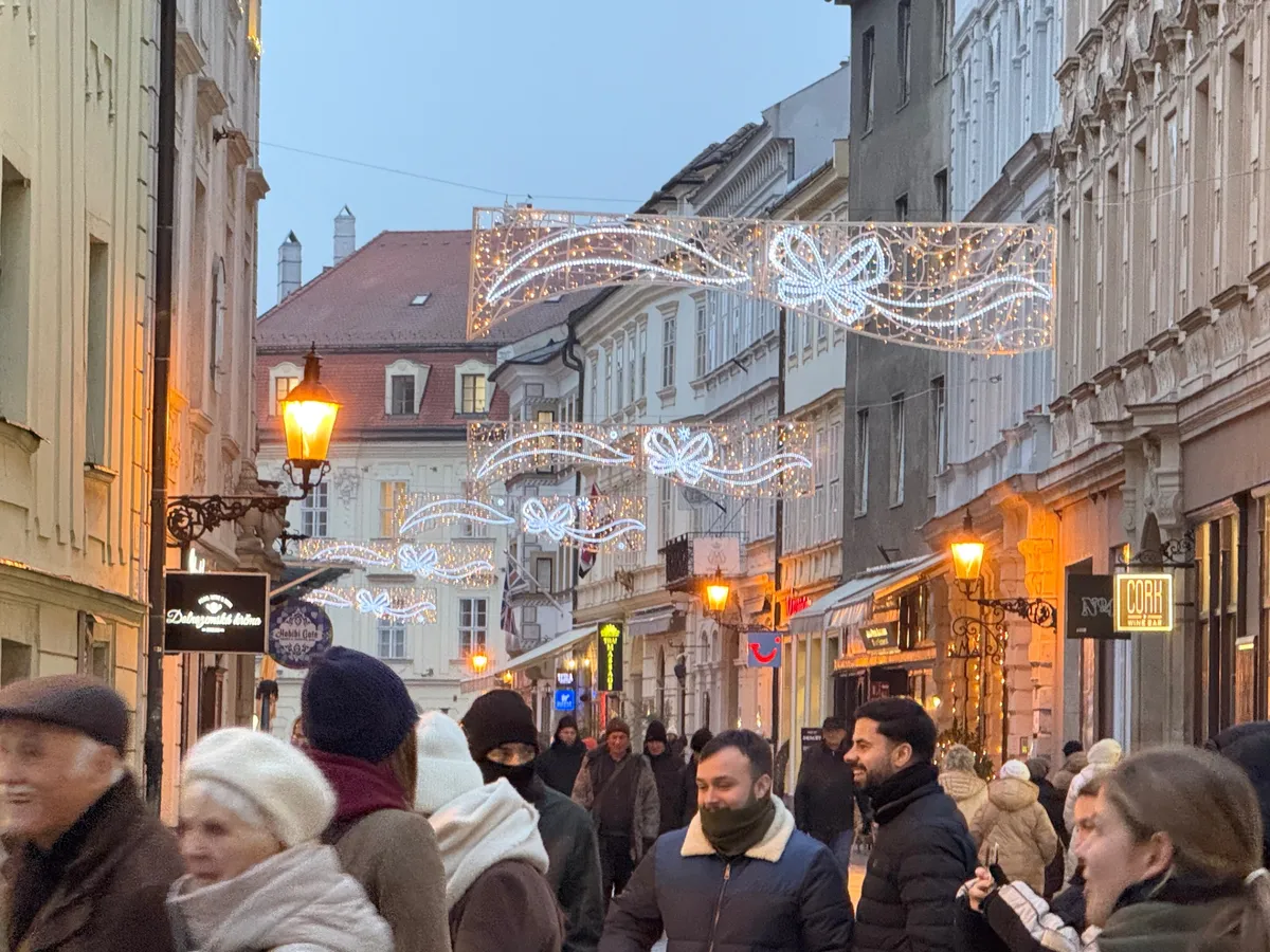 Charming Unknown Christmas market with festive decorations, lights, and bustling crowds at blue hour.