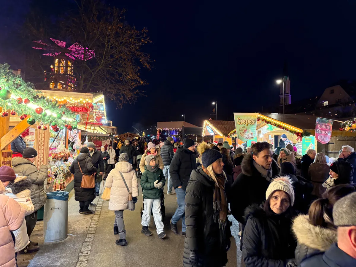 Lively Unknown Christmas market at dusk featuring festive decorations, lights, and crowds enjoying traditional food.