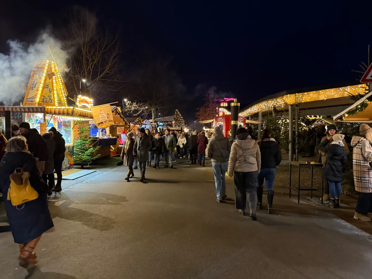 Unknown festive Christmas market with warm lights, decorations, and crowds enjoying the atmosphere.