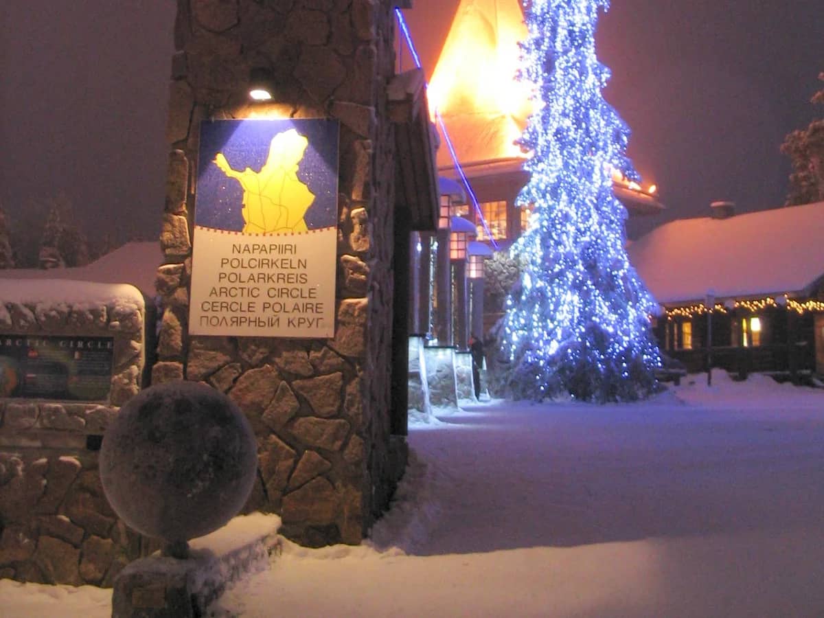 Rovaniemi Arctic Circle marker glows under winter twilight with Christmas tree