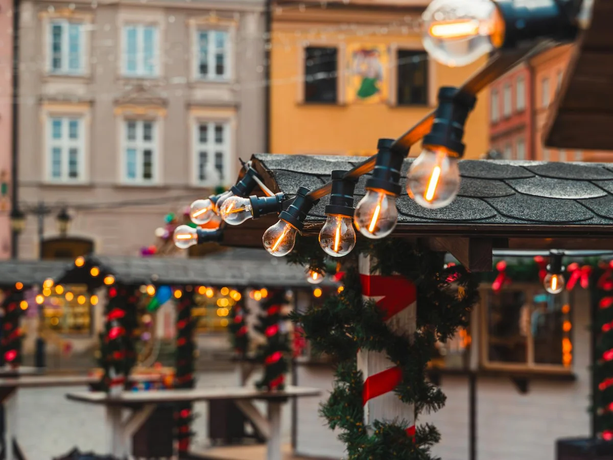 Arras glowing Edison bulbs illuminate a magical winter Christmas market