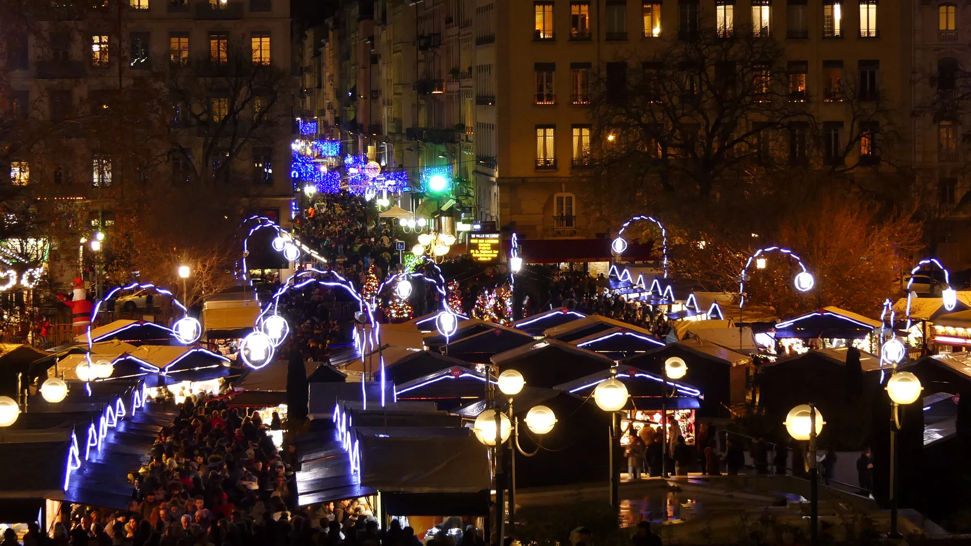 Lyon Christmas market illuminated by blue neon archways in winter