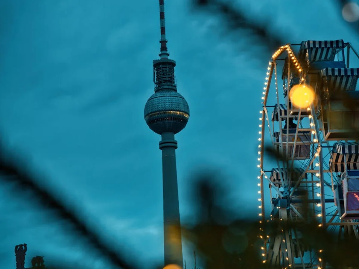 Berlin TV Tower illuminated at twilight beside a festive Ferris wheel during Christmas