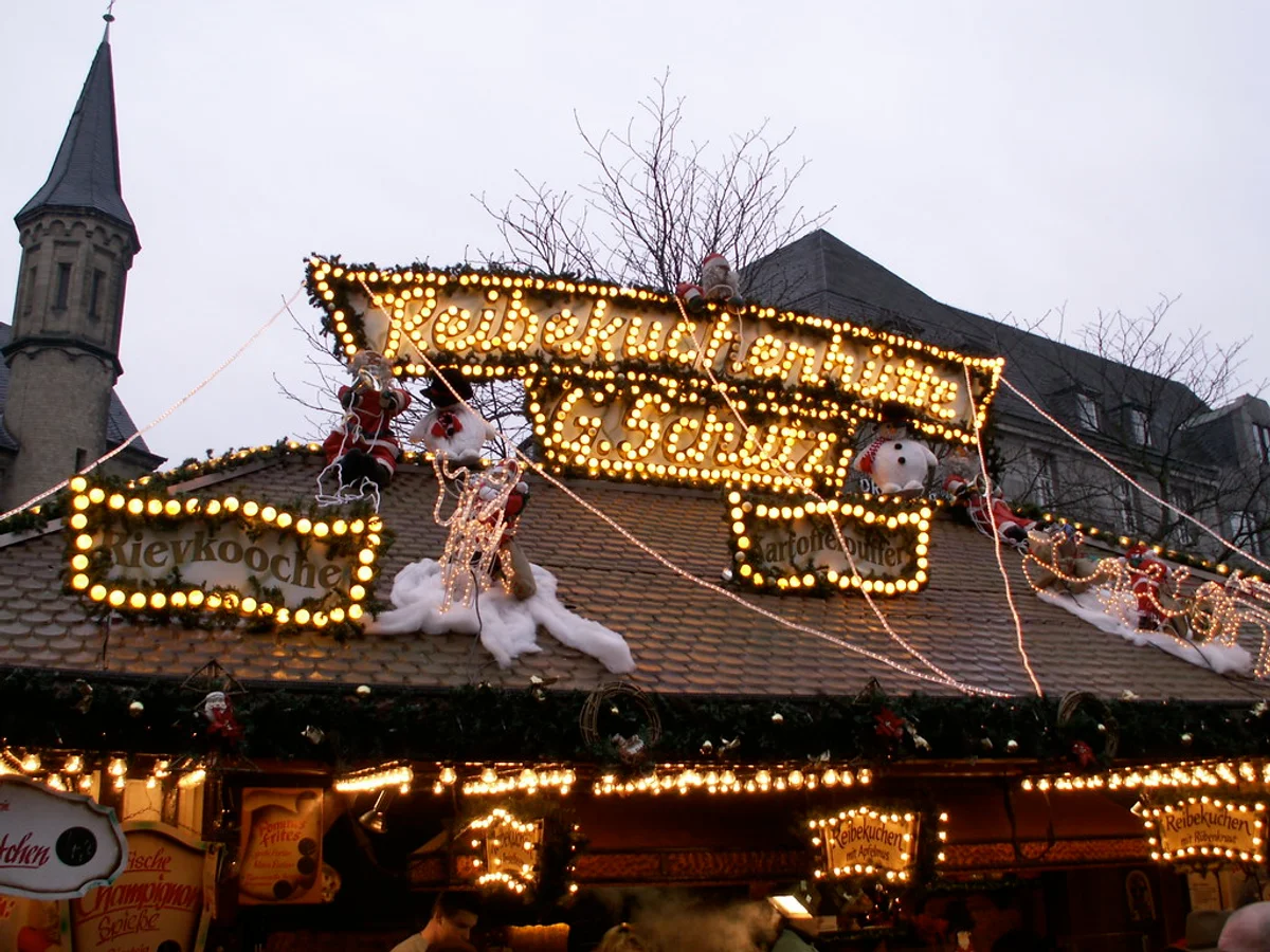 Bonner Weihnachtsmarkt - Münsterplatz illuminated at twilight in Bonn with the Minster spire as backdrop.