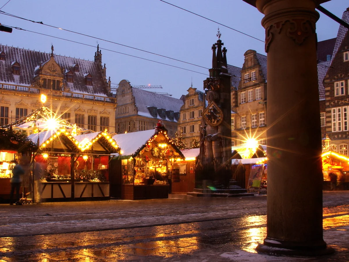 Weihnachtsmarkt Bremen illuminated stalls and Town Musicians statue at Bremer Marktplatz during twilight