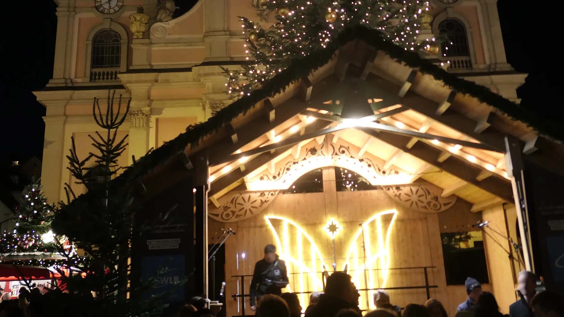 Ludwigsburger Barock-Weihnachtsmarkt illuminated by blue hour light in Ludwigsburg, featuring St. Martin's Church and festive crowd.