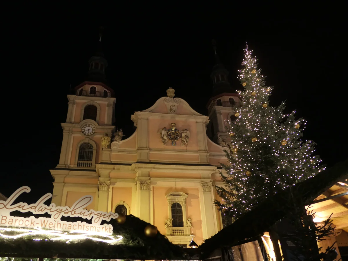 Ludwigsburger Barock-Weihnachtsmarkt illuminated with a festive tree in Ludwigsburg, showcasing St. Martin's Church at night.