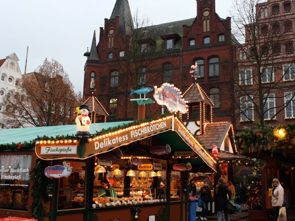 TO HUUS Weihnachtsmarkt stall selling Fischbroetchen in Lüneburg, warm festive atmosphere, historic Altstadt