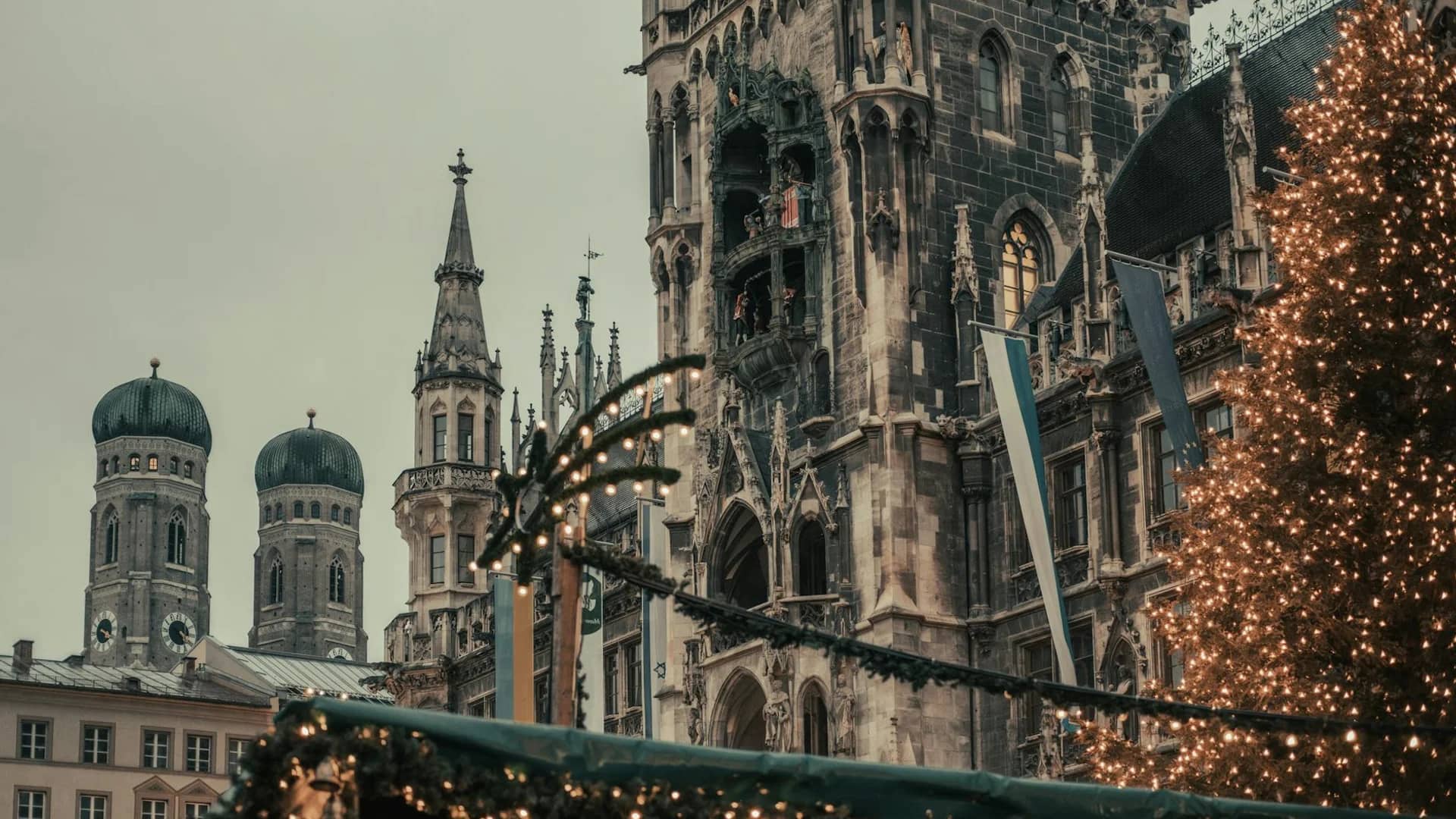 Munich Rathaus and Frauenkirche towers adorned with Christmas lights and garland