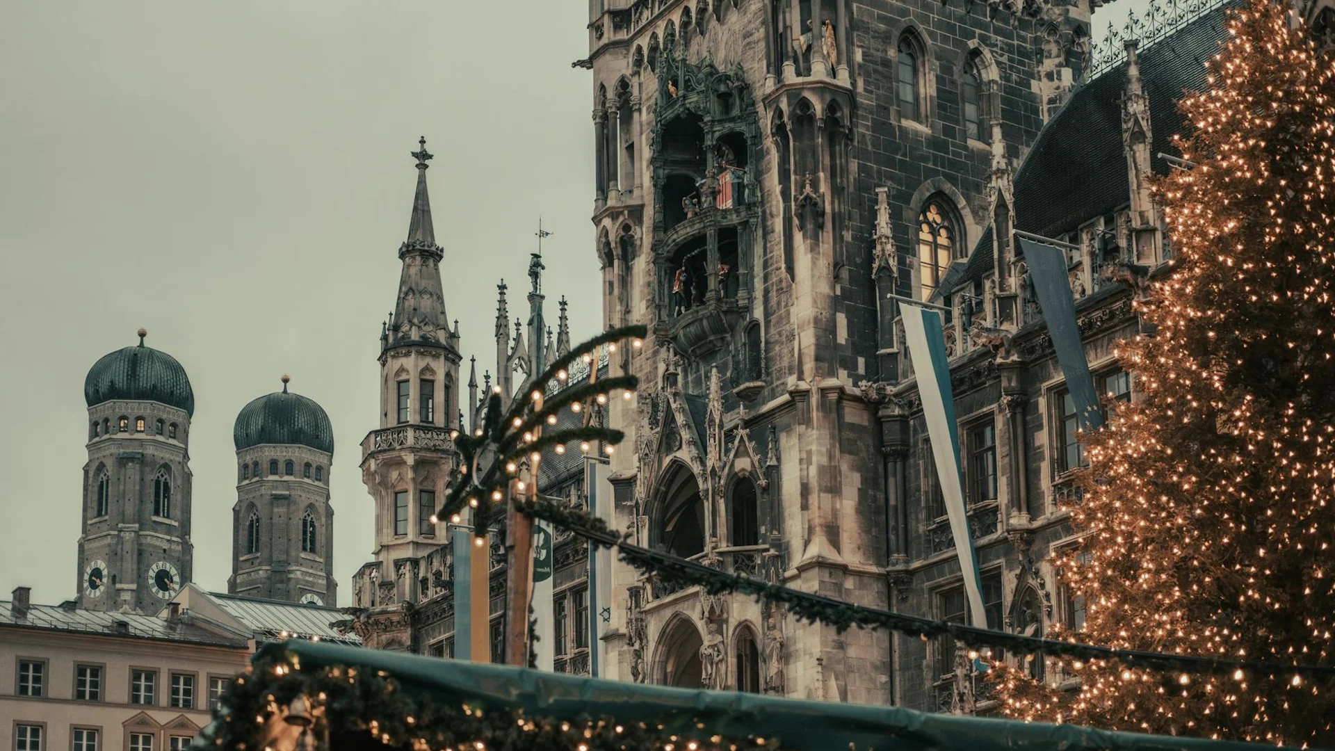 Munich Rathaus and Frauenkirche towers adorned with Christmas lights and garland