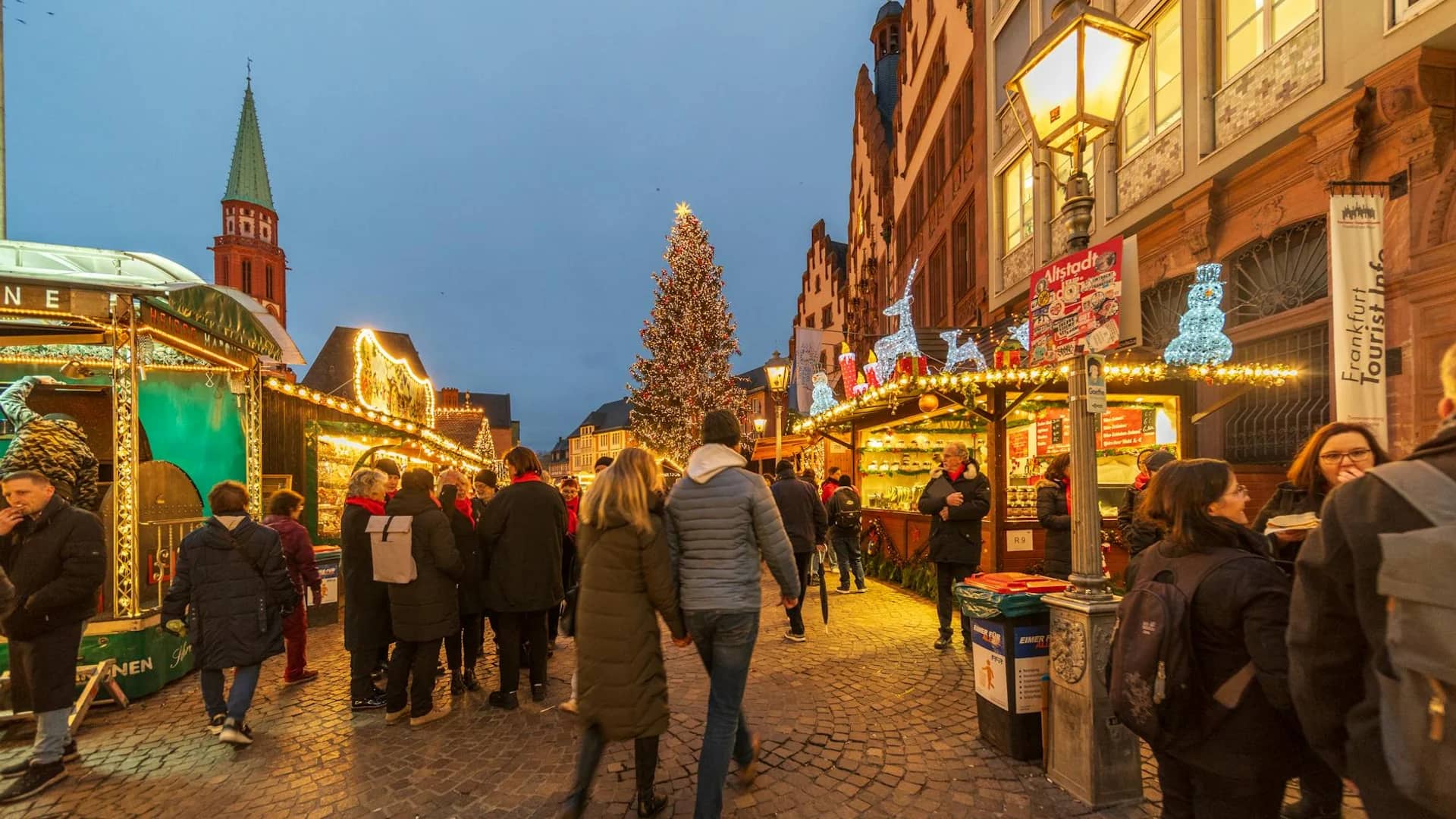 Trier red church tower shines over a bustling Christmas market at twilight