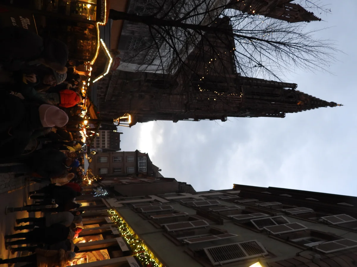 Ulmer Weihnachtsmarkt vibrant crowd at twilight in Ulm with Ulm Minster spire