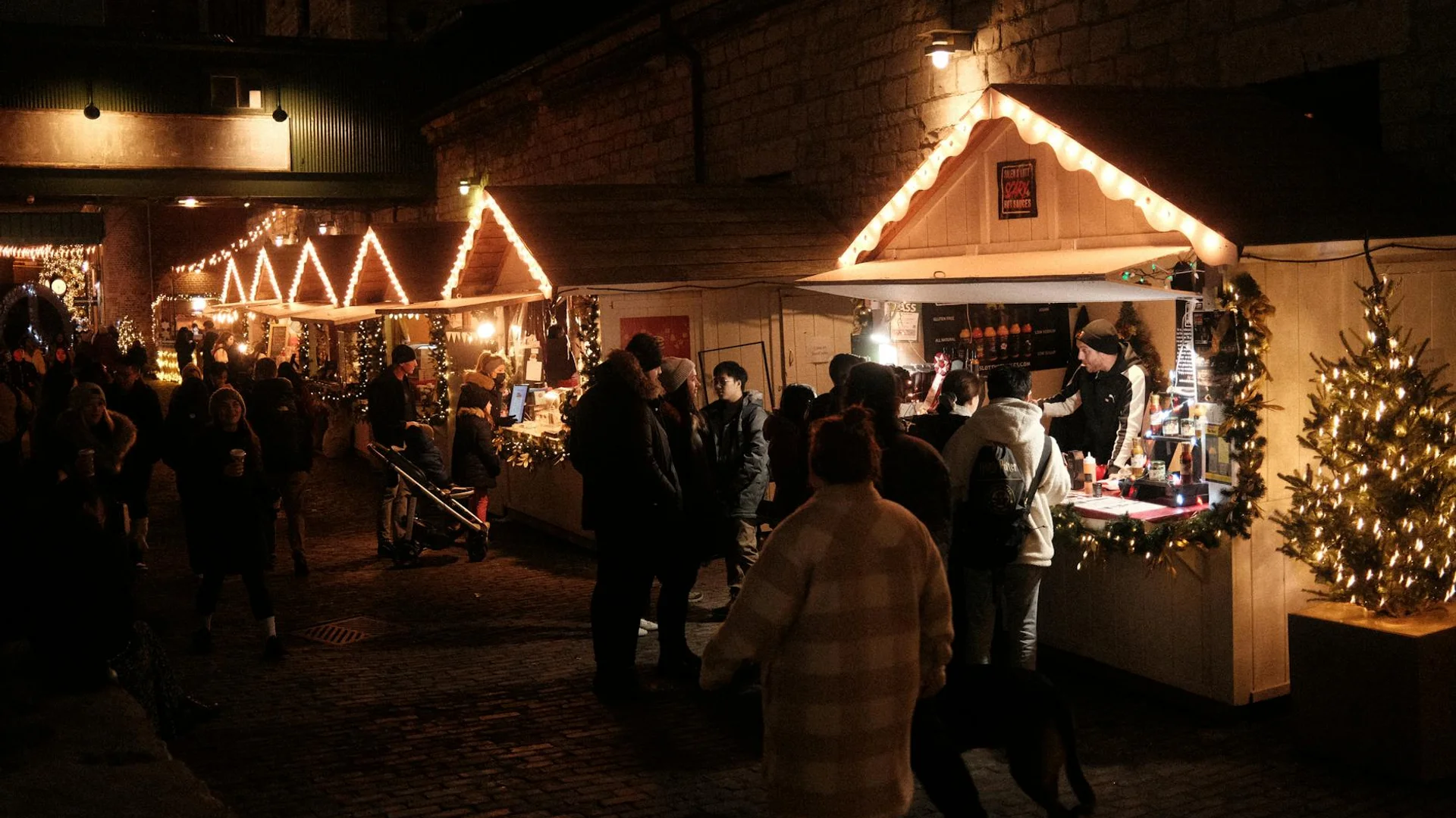 Waterford blue hour Christmas market with warmly-lit stalls and festive garland