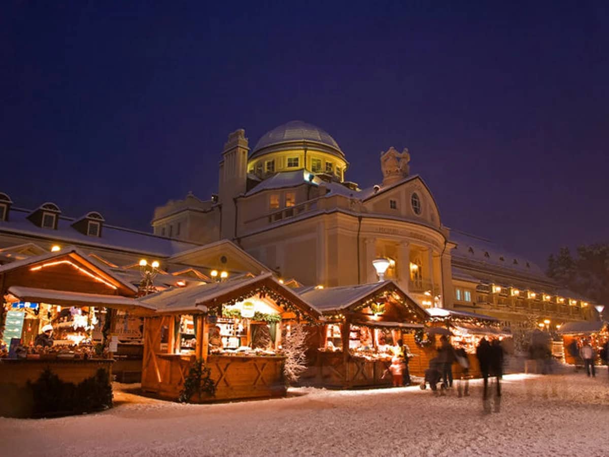 Merano's iconic dome shines over a festive Christmas market at twilight