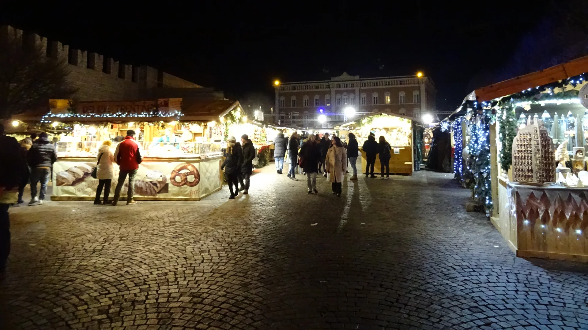 Trento Christmas market at dusk with festive stalls and historic architecture