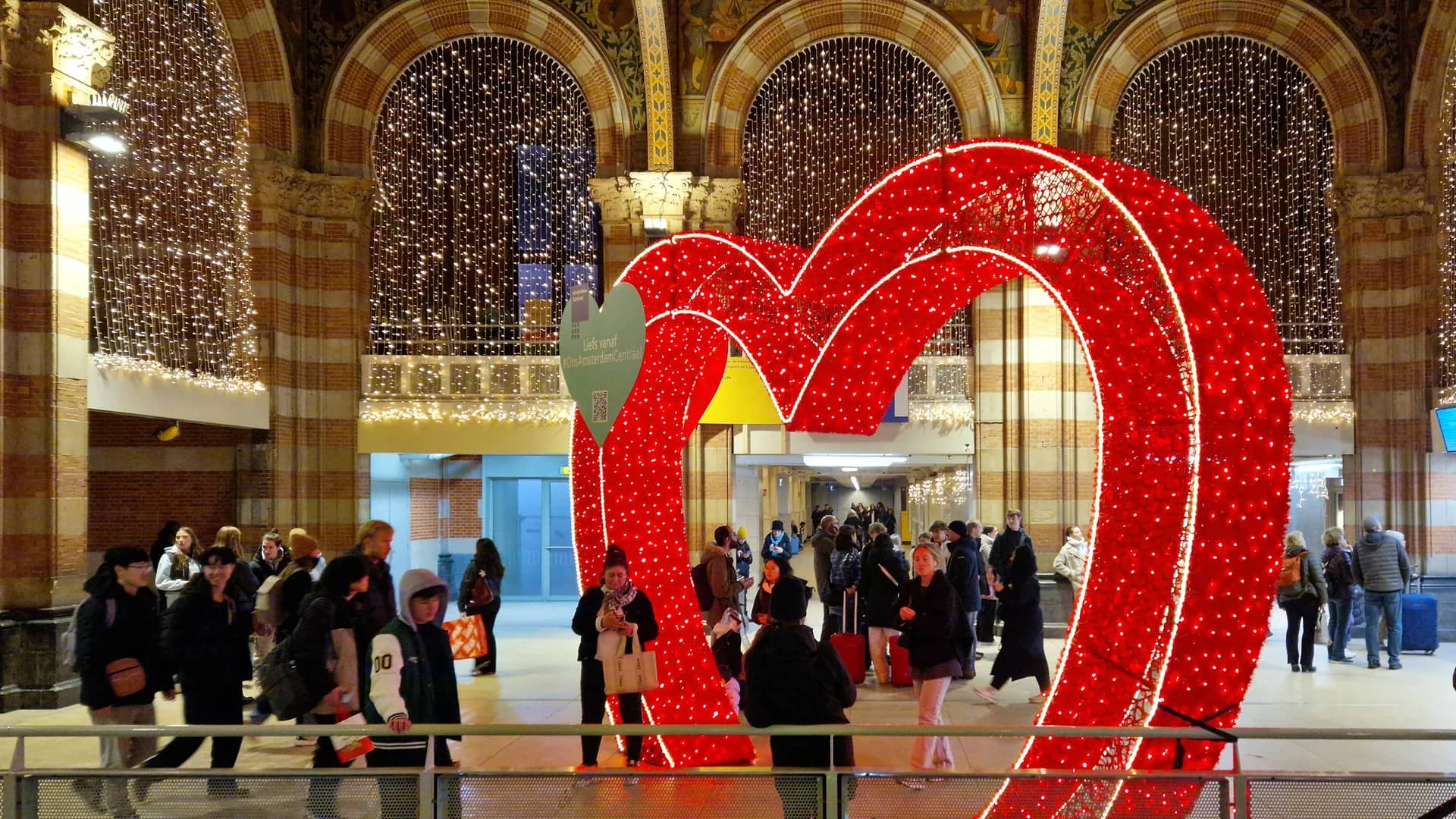 Amsterdam Central Station arches frame a heart-shaped light installation during Christmas season