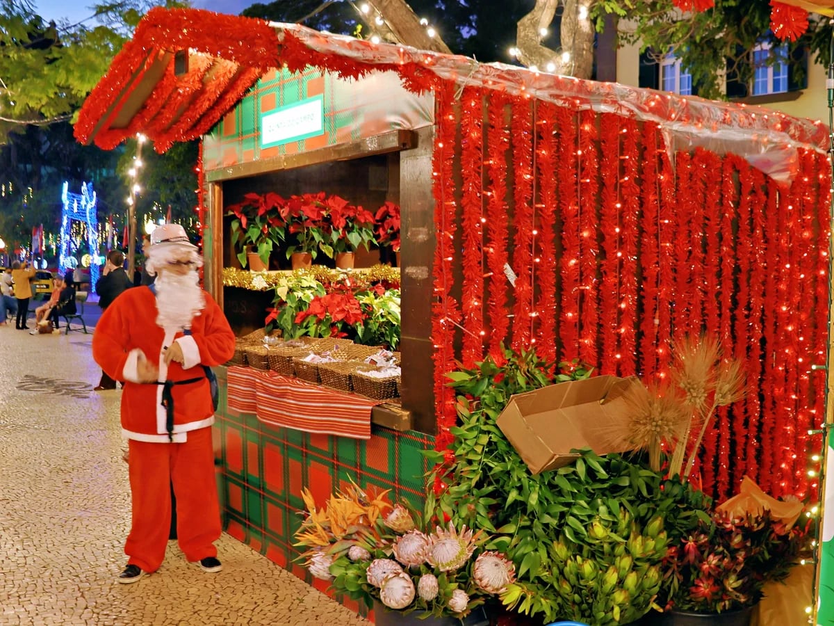 Mercadinho de Natal festive stall with Santa in Funchal, warm twilight atmosphere on Avenida Arriaga