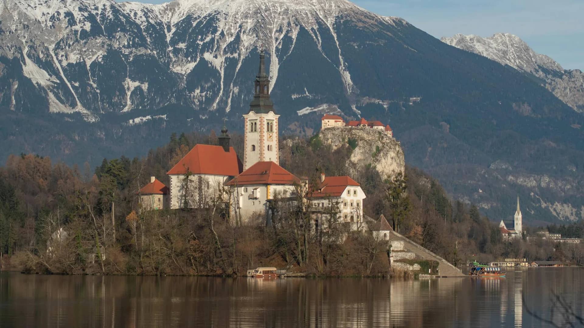 Bled Island Church surrounded by snow-capped Julian Alps in winter