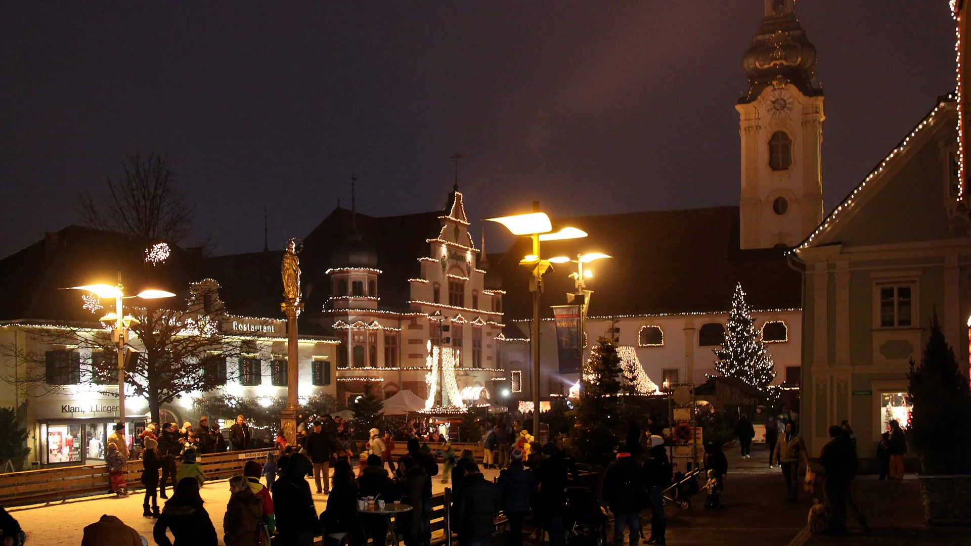 Čarobni Maribor - Main Square illuminated by festive lights, Maribor's Cathedral spire shines above a bustling Christmas market atmosphere.