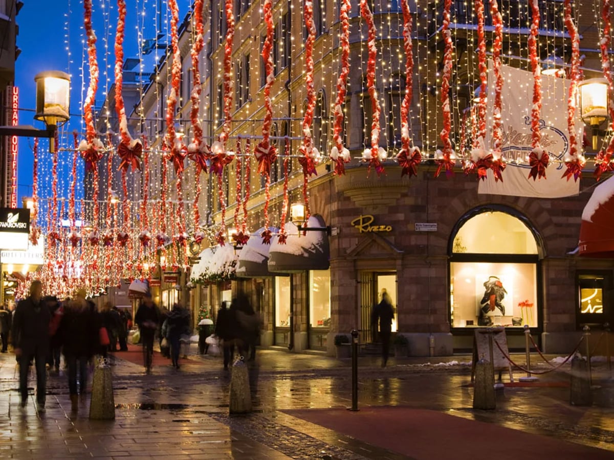 Stockholm Biblioteksgatan adorned in red and gold garlands during winter twilight