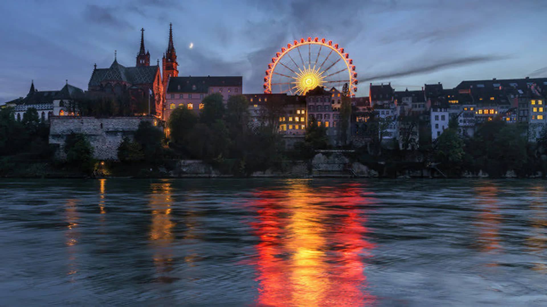 Basel illuminated Ferris wheel and Münster Cathedral at Christmas twilight