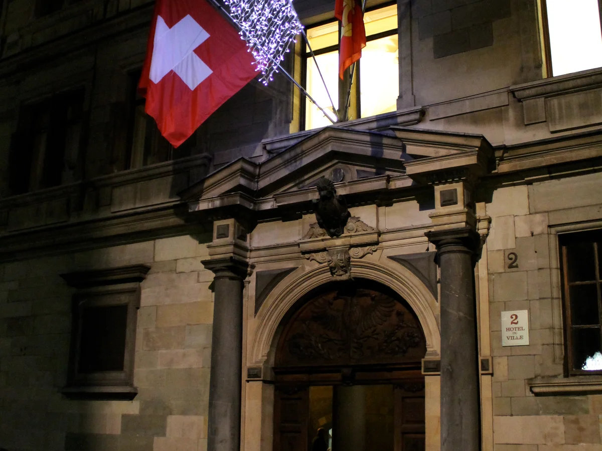 Geneva landmark with Swiss flag illuminated by festive blue lights during Christmas season