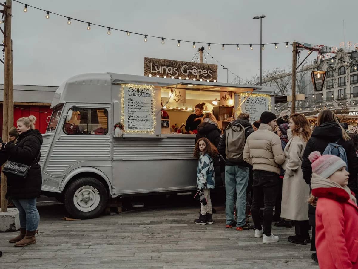 Zurich Christmas market scene with vintage crepe food truck and Parkhaus Opera