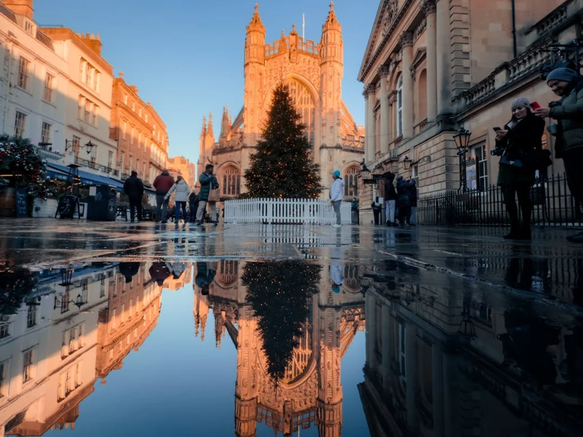 Bath Abbey's Gothic spires reflect in a puddle during Christmas season