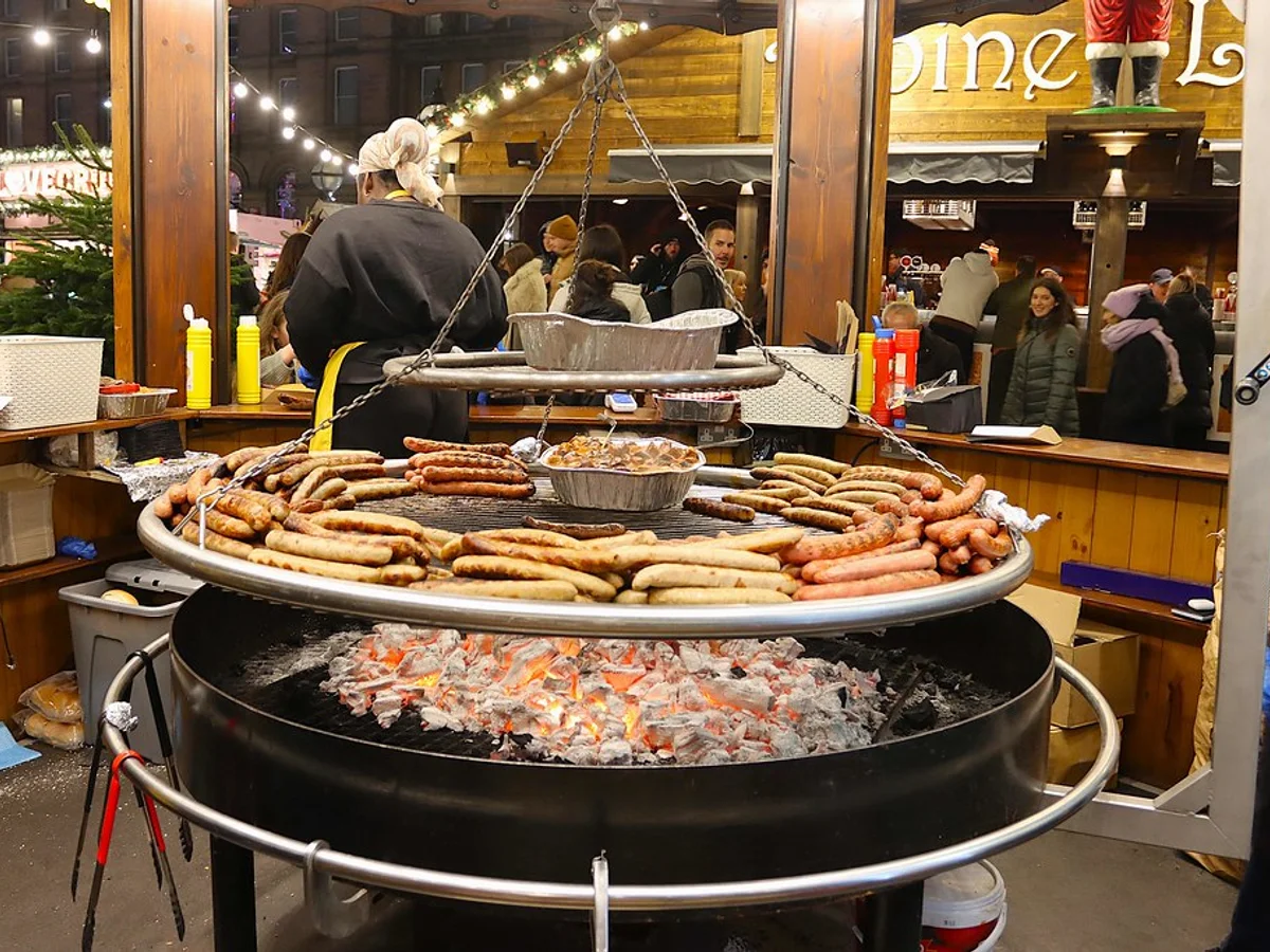 Liverpool Christmas Market food stall serving traditional sausages at St George's Plateau, warm evening atmosphere
