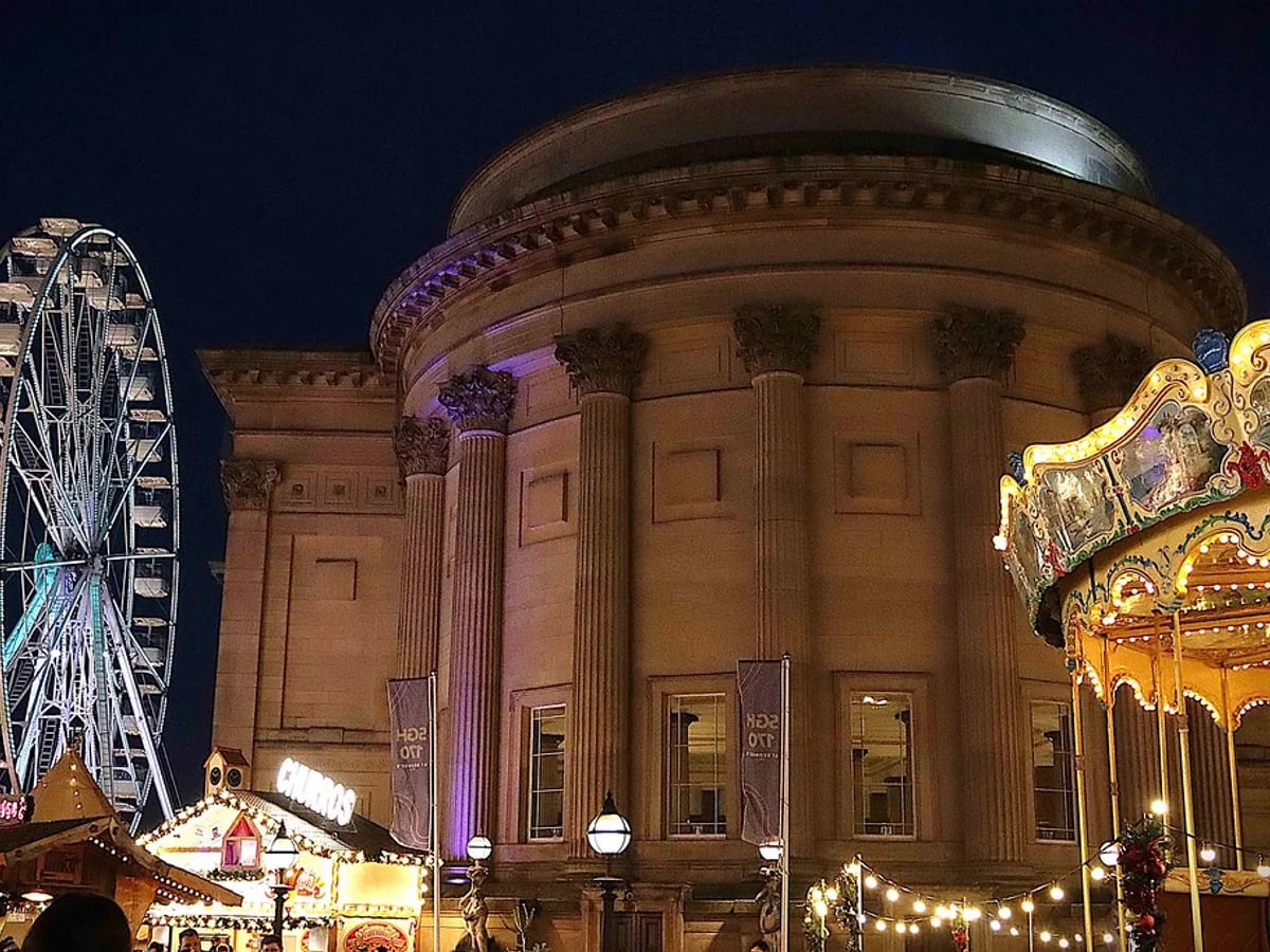 Liverpool Christmas Market's festive stalls and illuminated St George's Hall at twilight in Liverpool.