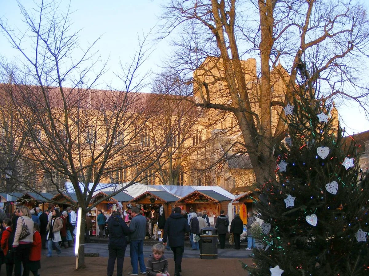 Winchester Cathedral Christmas Market bustling with crowds in Winchester, warm atmosphere beneath cathedral facade