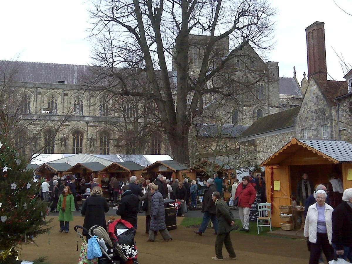 Winchester Cathedral Christmas Market bustling with visitors in Winchester, festive atmosphere by the cathedral.