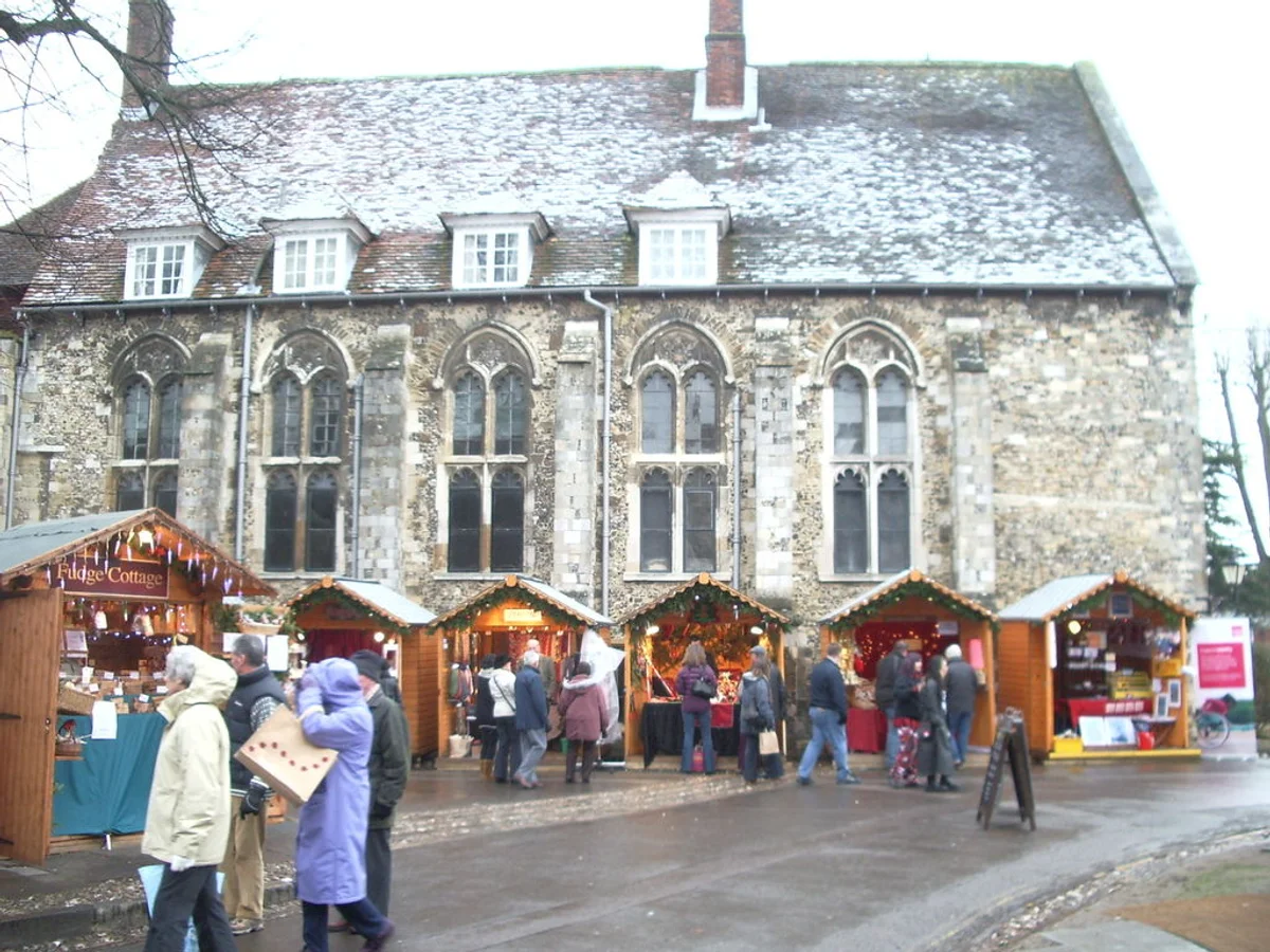Traditional wooden stalls glow warmly at Winchester Cathedral Christmas Market in Winchester, set against Gothic architecture.
