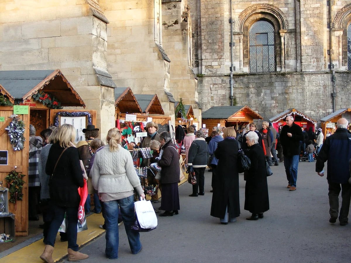 Winchester Cathedral Christmas Market festive atmosphere with wooden chalets in Winchester against the cathedral backdrop