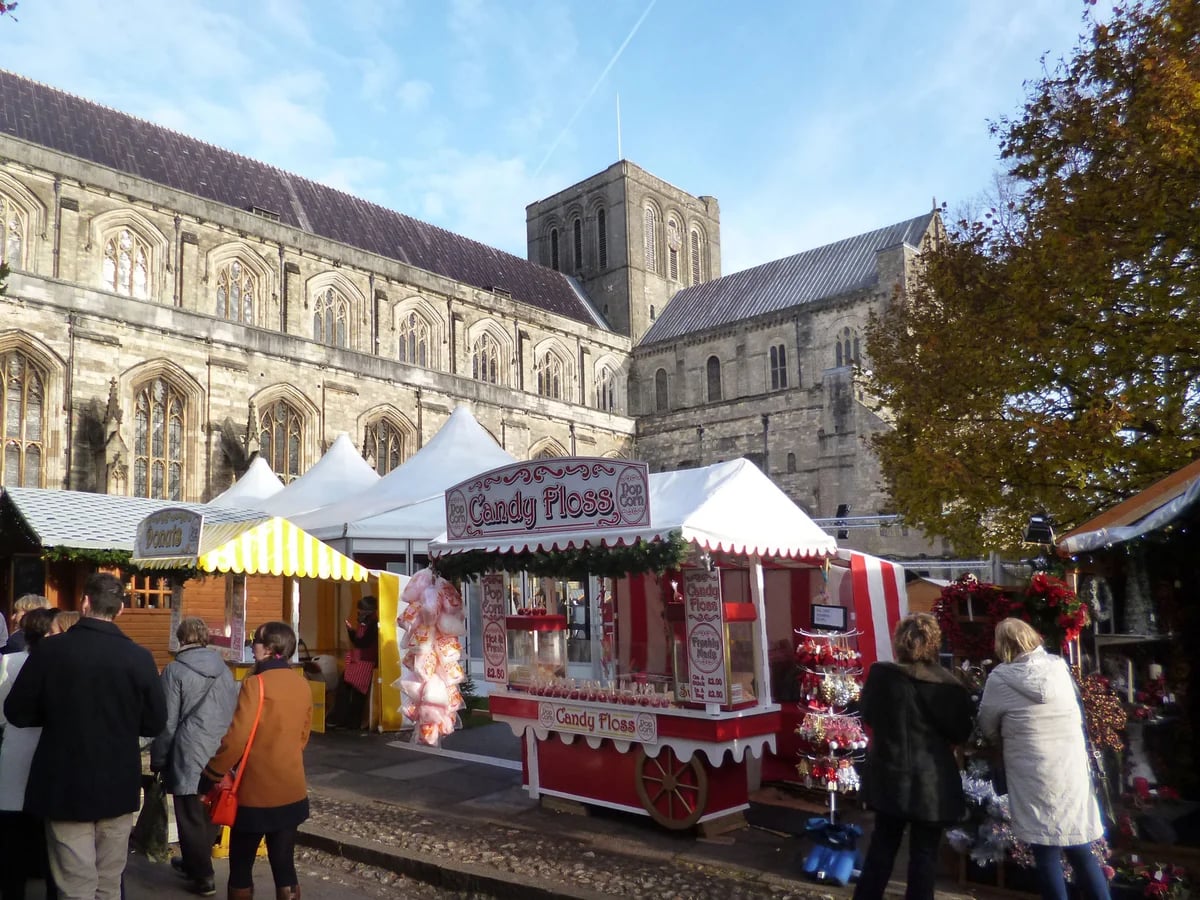 Winchester Cathedral Christmas Market with iconic Gothic architecture in Winchester, showcasing festive stalls and a lively atmosphere.